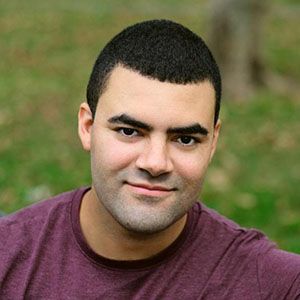 Aaron Parker Fouhey headshot. He wears a burgundy t-shirt and has a warm, closed mouth smile.